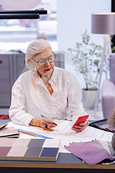 Graceful female chief officer in years mindfully checking her phone