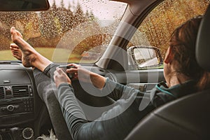 Graceful female palms holding hot tea thermos mug. She sitting on co-driver seat inside modern car,putting legs on dashboard
