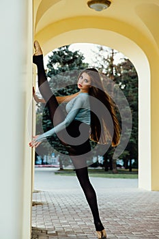 Graceful girl ballerina posing on the arches of the vintage theater.