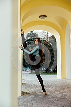 Graceful girl ballerina posing on the arches of the vintage theater.