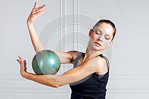 A graceful girl with a gym ball. The concept of sports, rhythmic gymnastics, sports for women.