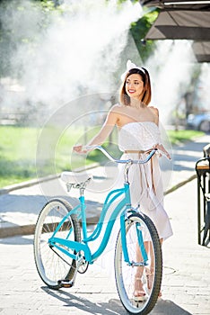 Graceful girl holds blue vintage bicycle in the summer