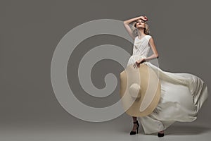 Graceful girl posing in a fluttering white dress.