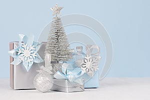 Graceful home decor for christmas celebration - pastel blue and metallic gift boxes with silver christmas tree, shiny ball.