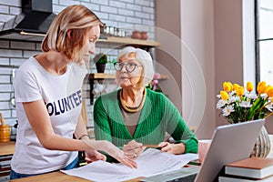 Graceful lady having conversation with retired woman about loan documents