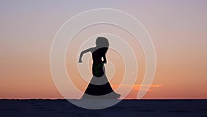 Graceful movements of a dancer, dancing belly dance while on the beach. Silhouettes