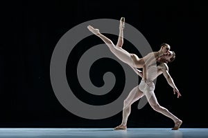 Graceful performance. Talented, artistic young woman and man, ballet dancers dancing against black studio background