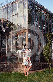 Graceful woman in dress on background of greenhouse building