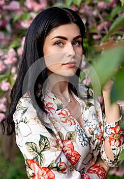 Graceful woman with perfect skin near flowering tree