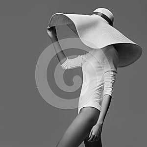 A graceful woman posing with a large wide-brimmed hat.