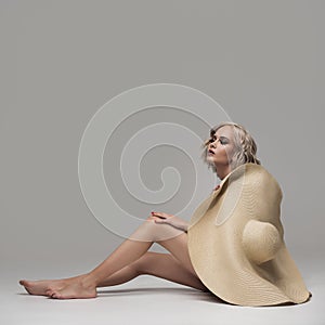 A graceful woman posing with a large wide-brimmed hat.