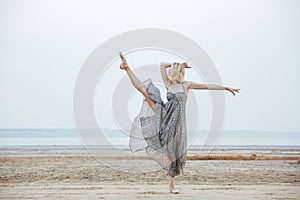 Graceful young woman dancer dancing on the beach