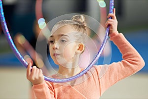 Gracefulness. Little girl, child, rhythmic gymnast training indoors, doing exercise with hoop. Concept of sport