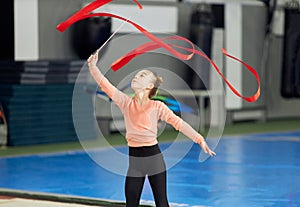 Gracefulness. Little girl, child, rhythmic gymnast training indoors, doing exercise with ribbon. Concept of sport