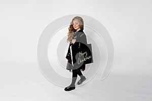 Gracious elegantly dressed little girl goes shopping with a bag