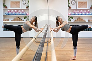 Gracious young ethnic ballerina exercising in studio