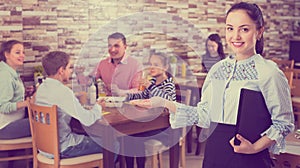 Gracious young waitress warmly welcoming guests to family cafe