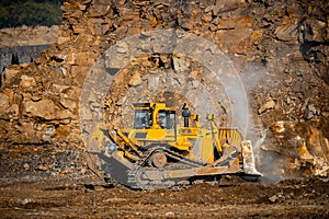 Grader excavator removes large stones after rock explosion blasting