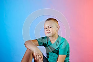 On a gradient bicolor color background, a cute baby posing in a turquoise t-shirt photo