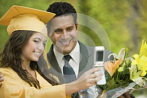 Graduate and father taking picture with cell phone outside