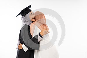 Graduate female student wearing toga hugging her friend