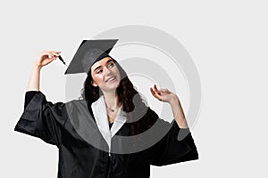 Graduate girl with master degree in black graduation gown and cap on white background. Happy young woman careerist have