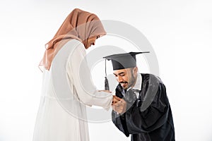 Graduate male student wearing toga shaking hands kissing mother's hand