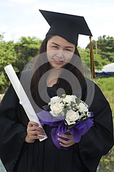 Graduate student holding flowers and diploma
