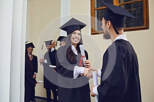 Graduate students shake hands at university college.