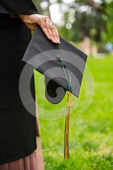 Graduate Wearing Gown and holding Motarboard In Park