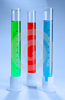 Graduated cylinders with different liquids on light background