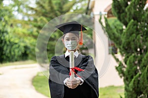 Graduated woman wear cap gown and Medical mask for protection virus holding diploma or certificated due Virus outbrake