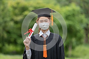 Graduated woman wear cap gown and Medical mask for protection virus holding diploma or certificated due Virus outbrake
