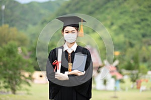 Graduated woman wear cap gown and Medical mask for protection virus holding diploma or certificated and tablet due Virus outbrake