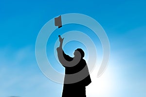 Graduates throwing hat on graduation day, silhouette