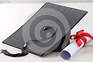 Graduation academic cap with diploma on wooden table background