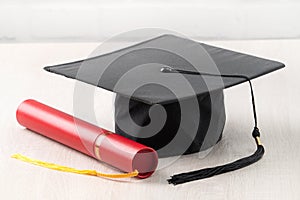 Graduation academic cap with diploma on wooden table background