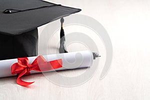 Graduation academic cap with diploma on wooden table background