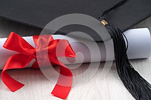 Graduation academic cap with diploma on wooden table background