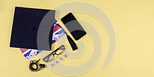 Graduation cap, glasses and and telephone.