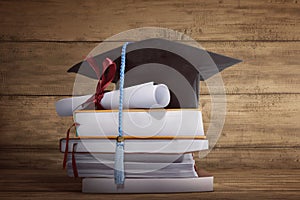 Graduation cap with graduation paper on a stack of book