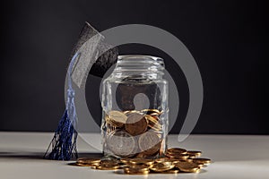 Graduation cap on jar with coins. Scholarship money concept