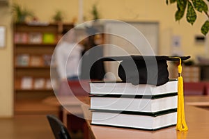 Graduation cap on a stack of books in the library.