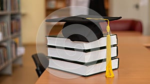 Graduation cap on a stack of books in the library.