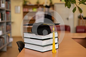 Graduation cap on a stack of books in the library.