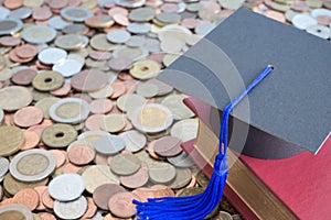 Graduation cap and textbook on many stacked coins cash - Scholarship, money saving or loan for education concept.