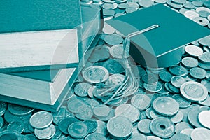 Graduation cap and textbook on many stacked coins cash - Scholarship, money saving or loan for education concept.