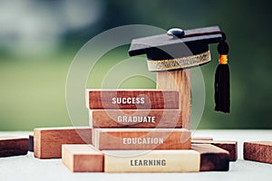 Graduation celebrating cap on wooden square blocks tower. Blank space for letter e.g education, success, graduate, etc. Ideas for
