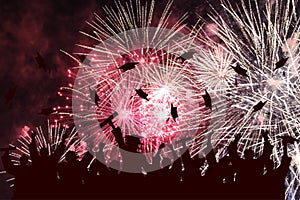 Graduation ceremony, fireworks in night sky. Silhouette of happy graduate students throwing academic square caps