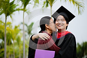 Graduation ceremony. Young female graduate hugging each other with her mother congratulate the student at the university